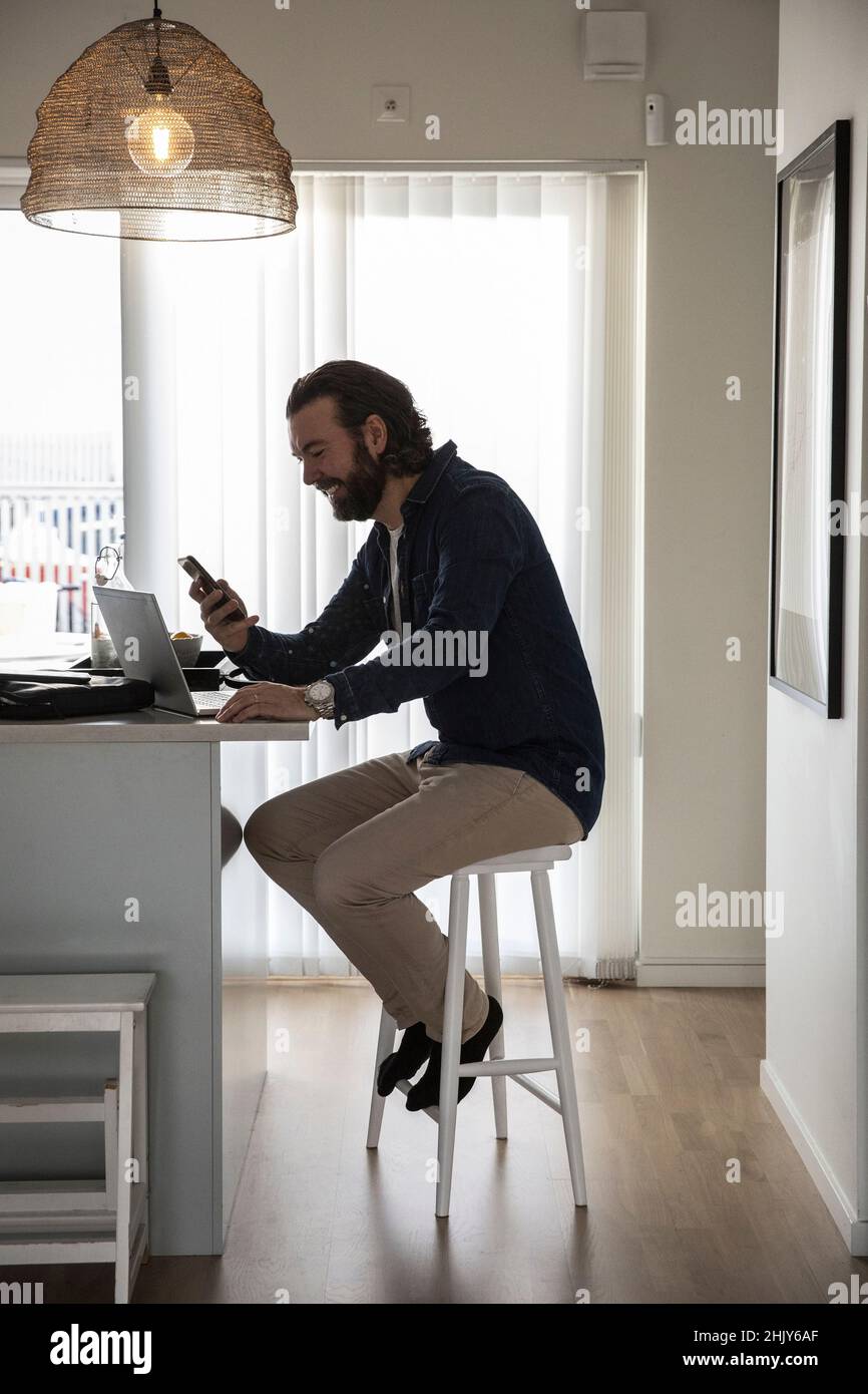 Mature businessman using smart phone while working at home Stock Photo