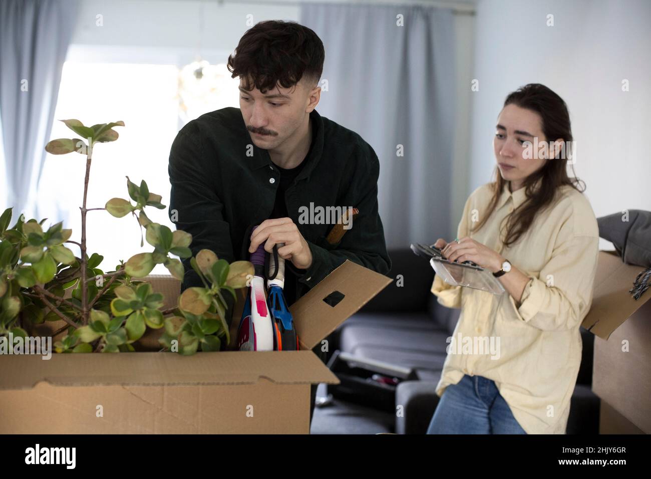 Young couple looking at box while relocating in new home Stock Photo