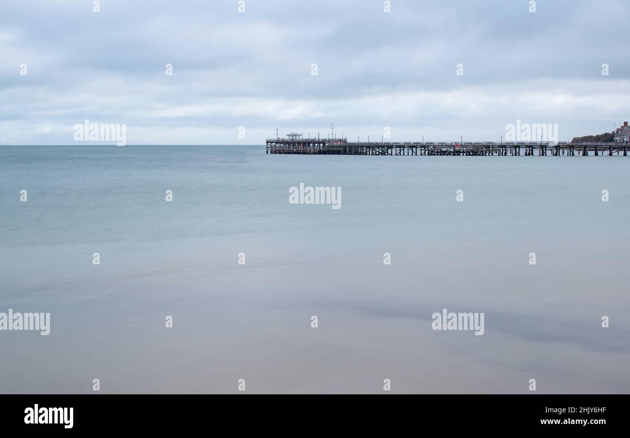 The old Swanage Pier on a still long exposure pale blue sea Stock Photo