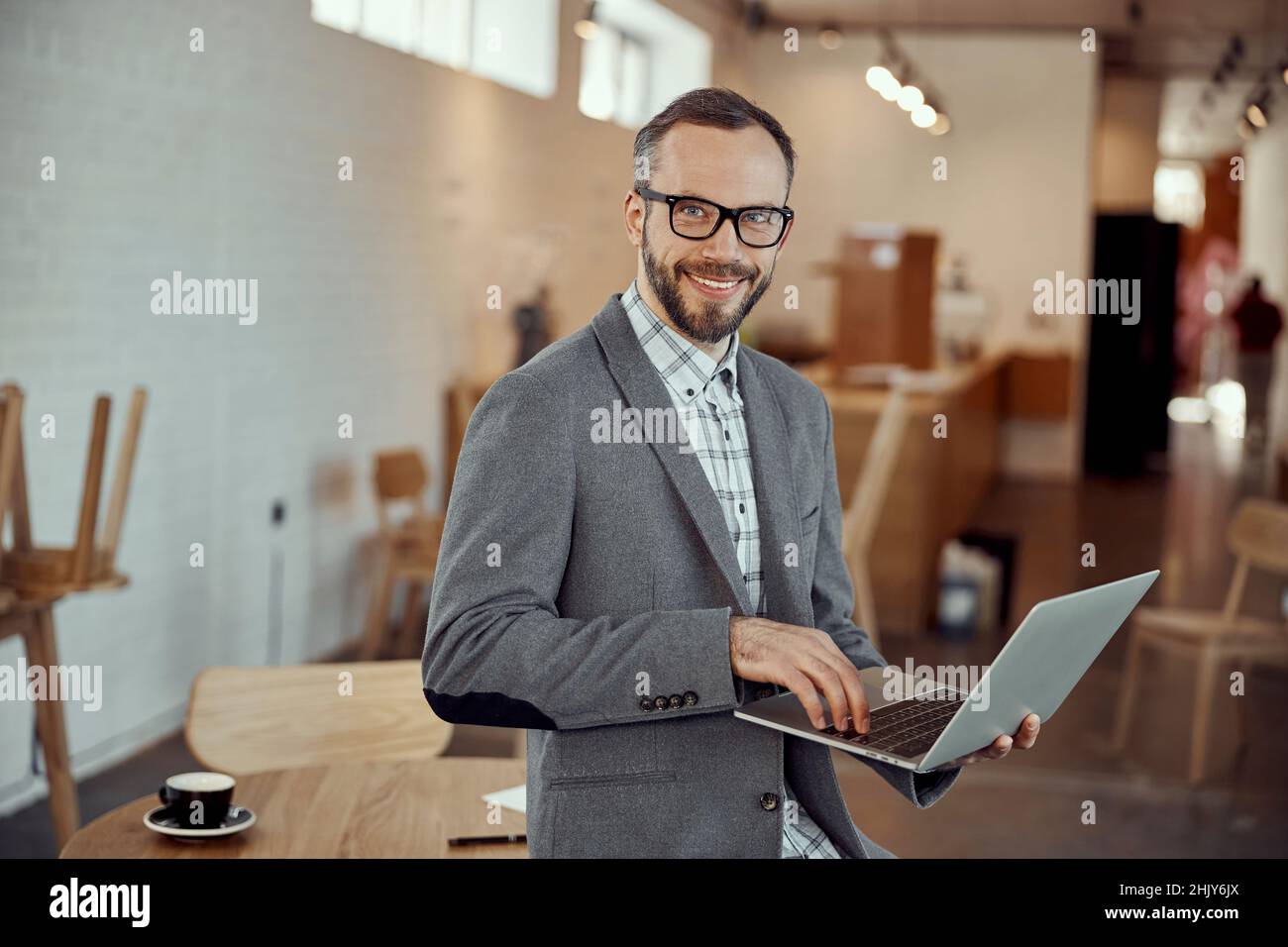 Joyful young man using notebook in cafe Stock Photo