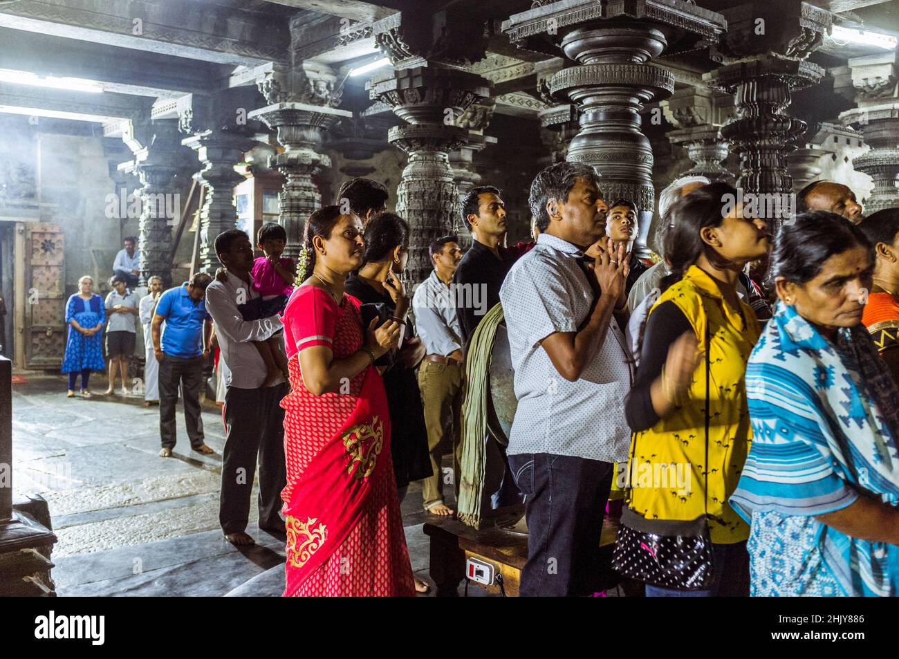 Belur, Karnataka, India : A group of devotees stand on prayer inside the 12th century Channakeshava Temple before the ritual puja ceremony. Stock Photo