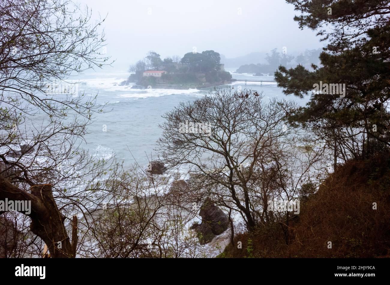 Oleiros, A Coruña province, Galicia, Spain - February 11th, 2020 : Santa Cruz castle on Santa Cristina islet on a foggy winter evening. Stock Photo