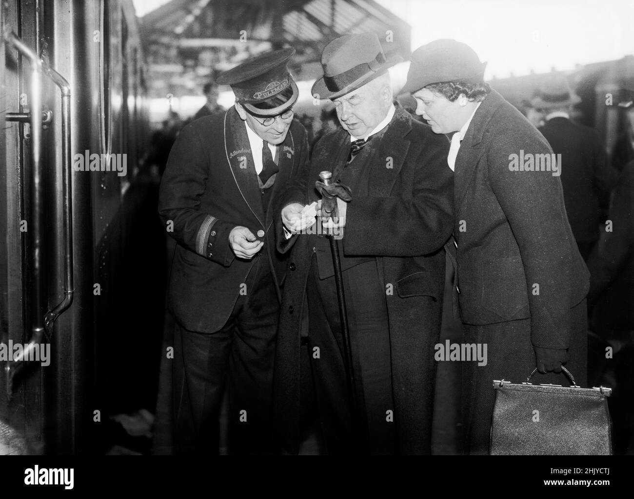 A railway attendant on a Pullman car, inspects the tickets of two passengers, at a station in England, c 1930 - 1940. Credit: The DL Archive Collection/Alamy Stock Photo