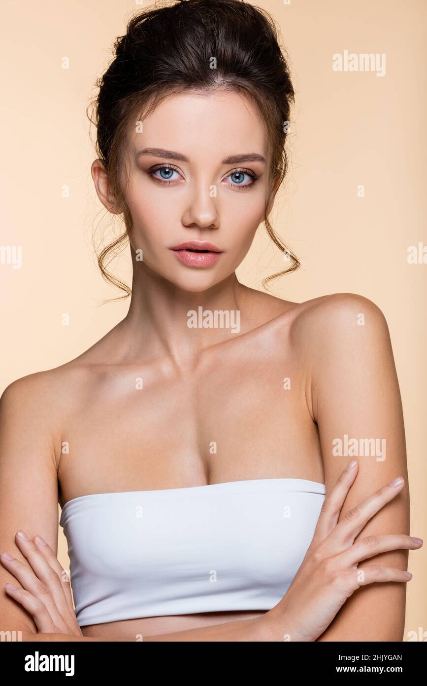 Pretty model in white top crossing arms isolated on beige Stock Photo