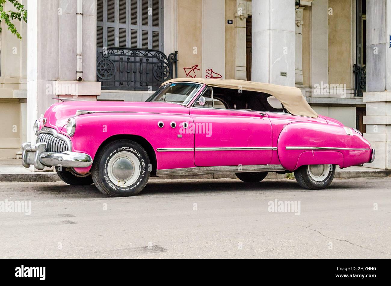 Pink Vintage Convertible Antique Car Parked Outside an Old Neoclassical Building at a Street of Patras, Greece Stock Photo