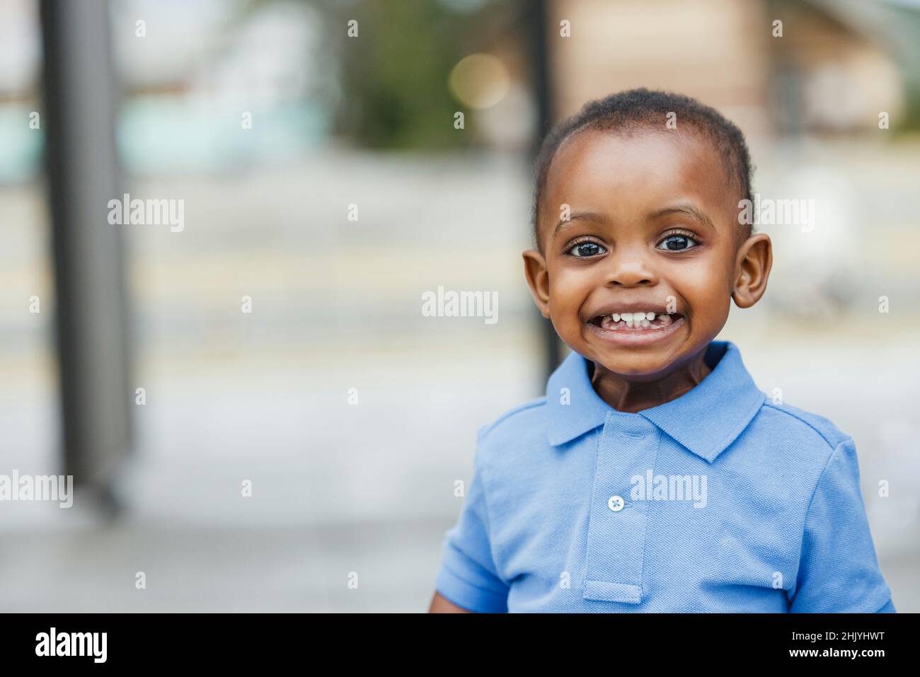 A cute one year old toddler almost preschool age African-American boy with big eyes smiling and looking away with copy space Stock Photo