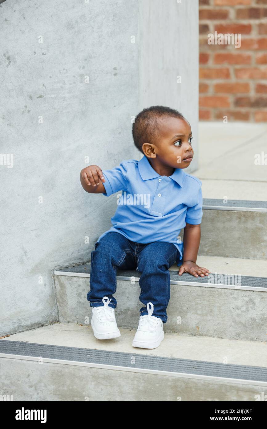 A cute one year old toddler almost preschool age African-American boy with big eyes smiling and looking away with copy space Stock Photo