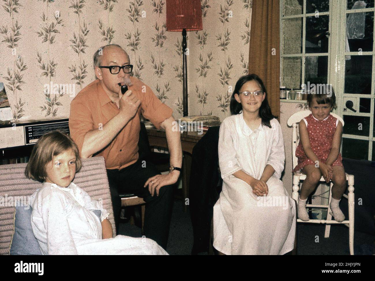 1960s, historical, three young girls, watching television with their father before bedtime, England, UK. The two older girls are in their night gowns and Dad is smoking a pipe. Stock Photo