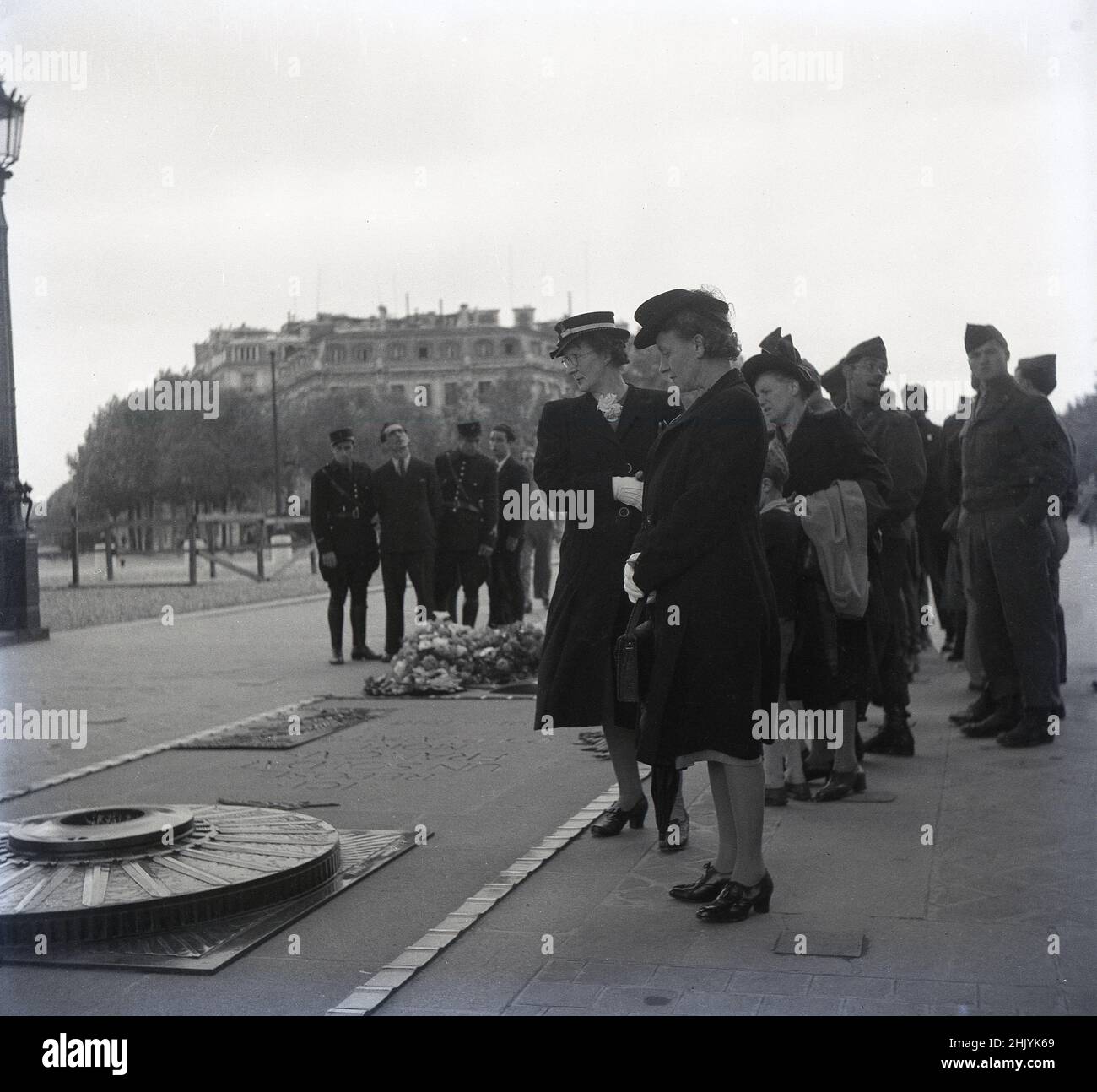 1950s, historical, lady civilians, some war widows, together with soliders, gather to pay their respects at the Tomb of the Unknown Solider at the base of the Arc de Triomphe, Paris, France. The burial site of a fallen French WW1 solider is a scared place, a permanent reminder of the enormous sacrifices made in the great war. Stock Photo