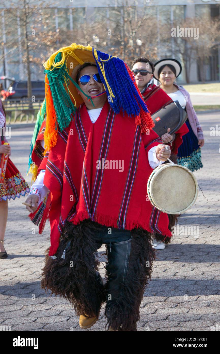 An Ecuadorian New Yorker plays the drums and dances wearing a colorful hat with long strings. In a park in Queens, New York City. Stock Photo