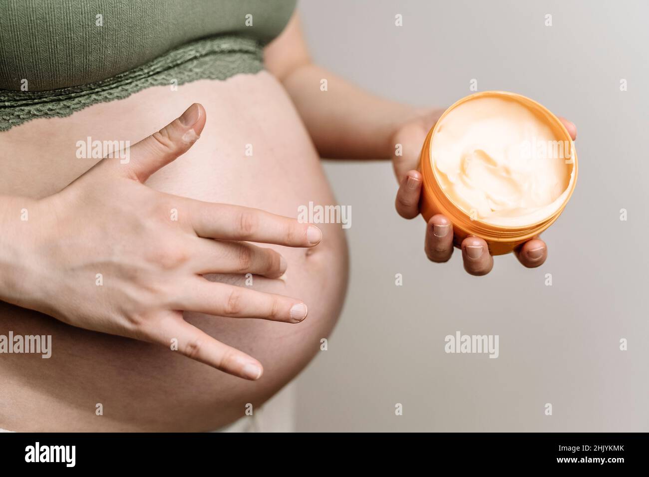 A pregnant woman uses a cream for stretch marks. Prevention of stretch marks on the abdomen and