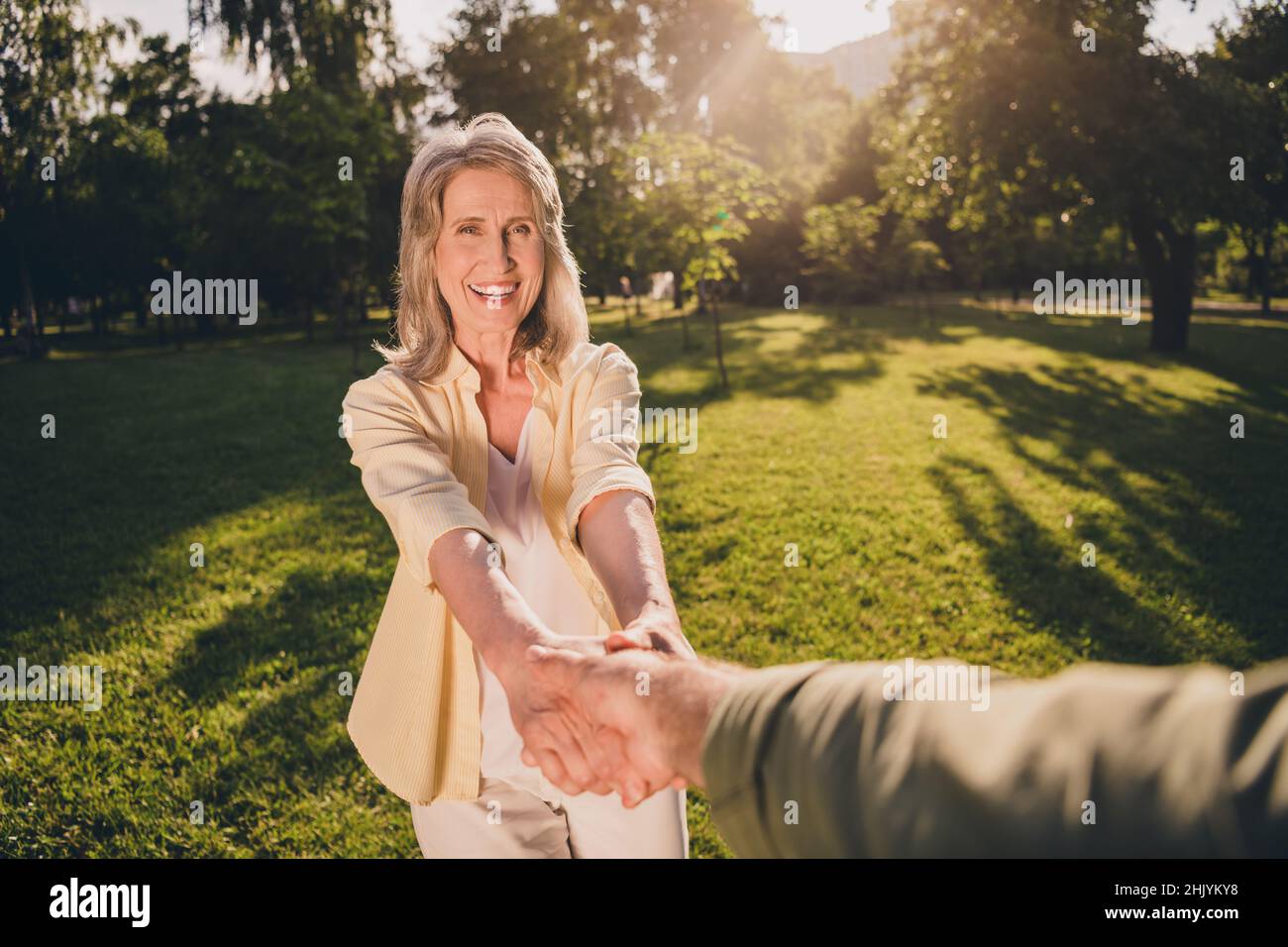 First point view portrait of attractive cheerful middle-aged couple holding hands spending time having fun on fresh air outdoors Stock Photo