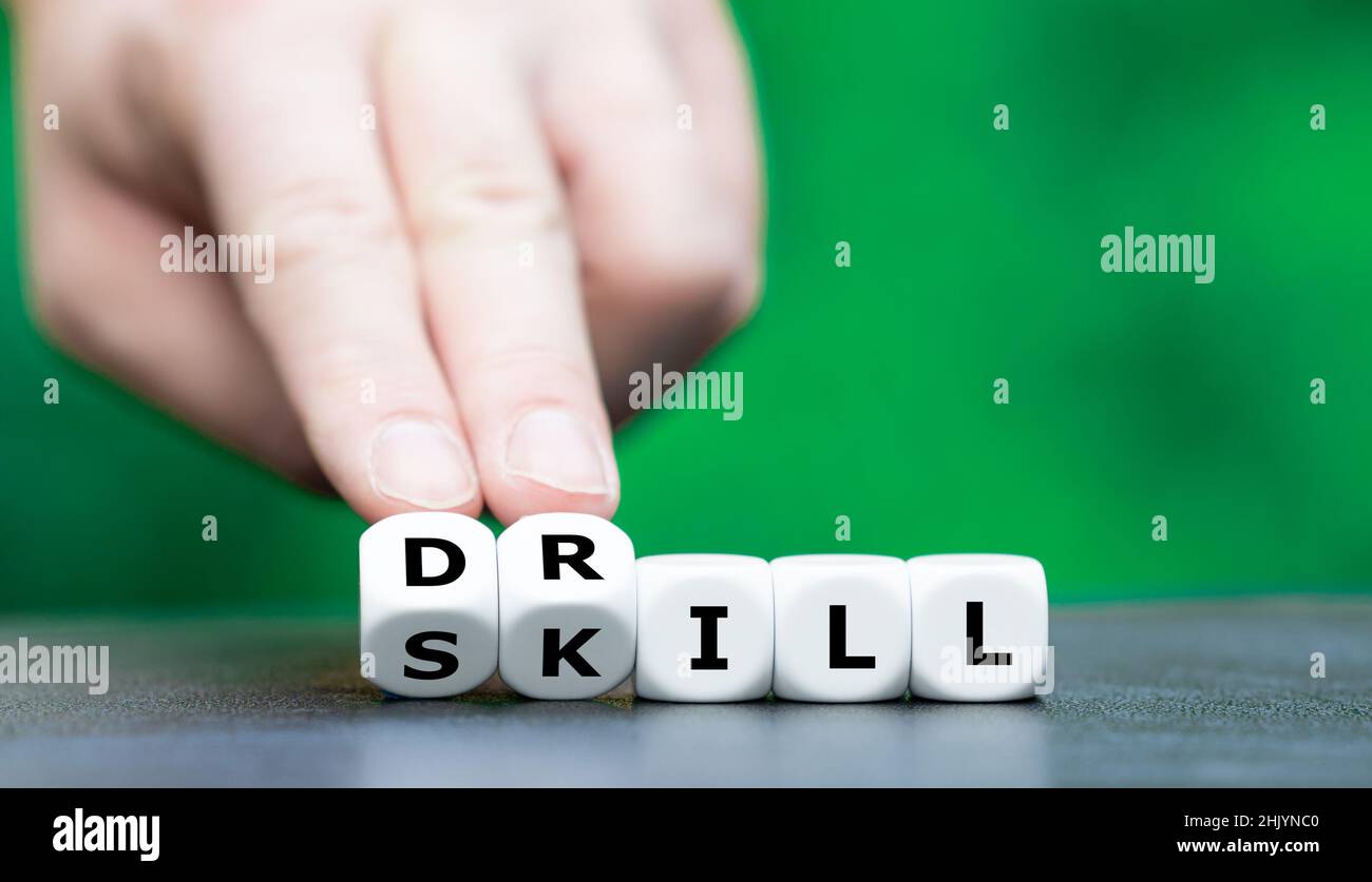 Drill or skill? Hand turns dice and changes the word skill to drill. Stock Photo
