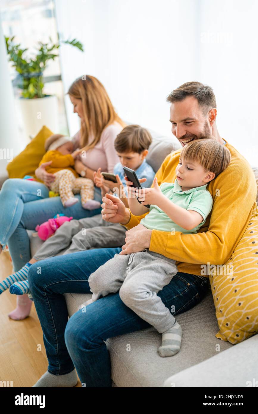 Parents with children playing games, using mobile apps on phone at home Stock Photo