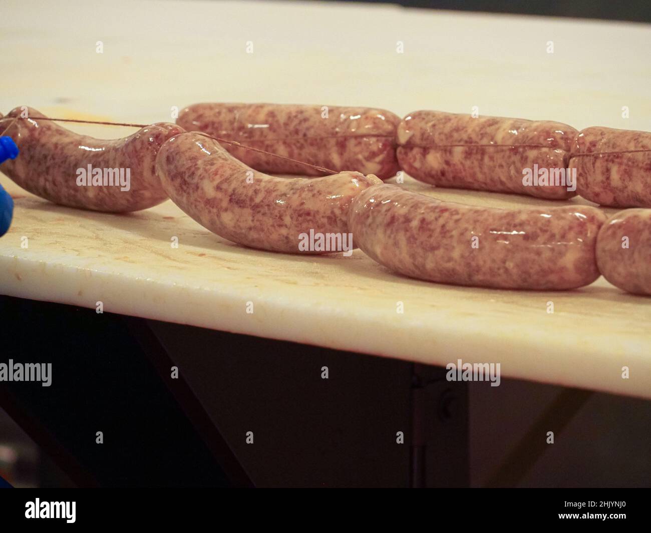 Factory Stuffing worker manufacturing, stuffing and tying sausages, salme and chorizo in ...