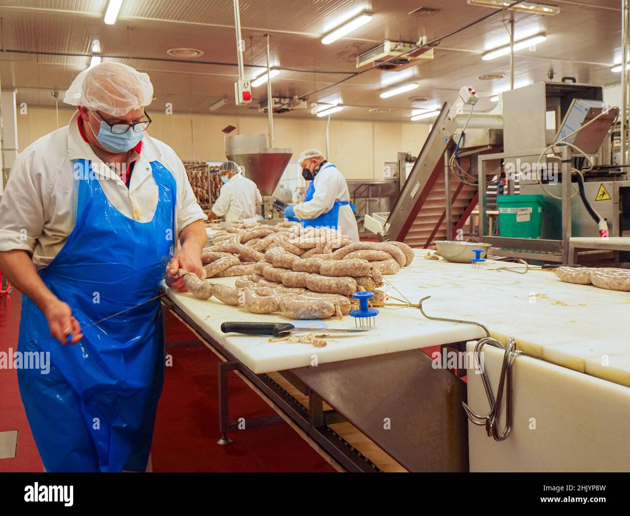 Factory Stuffing worker manufacturing, stuffing and tying sausages, salme and chorizo in ...