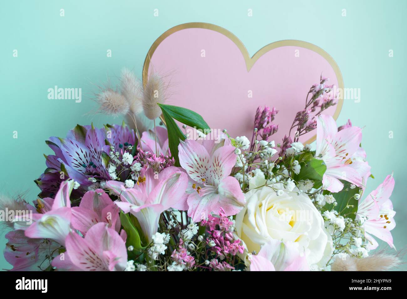 Delicate bouquet pink lilies, white roses, gypsophiles. Turquoise background. Pink Heart, copy space. Stock Photo