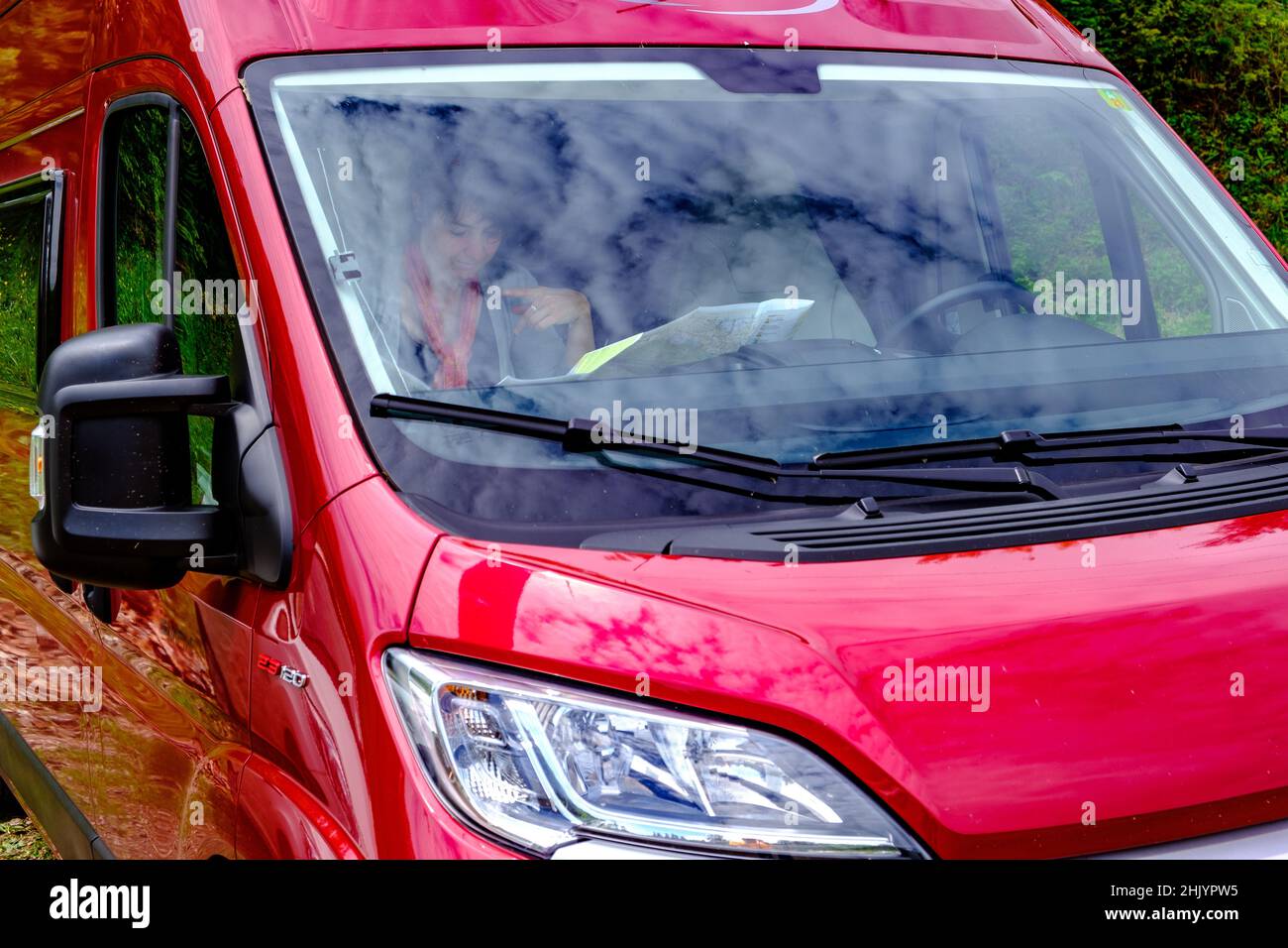 Woman studying a roadmap on her red camper van Stock Photo
