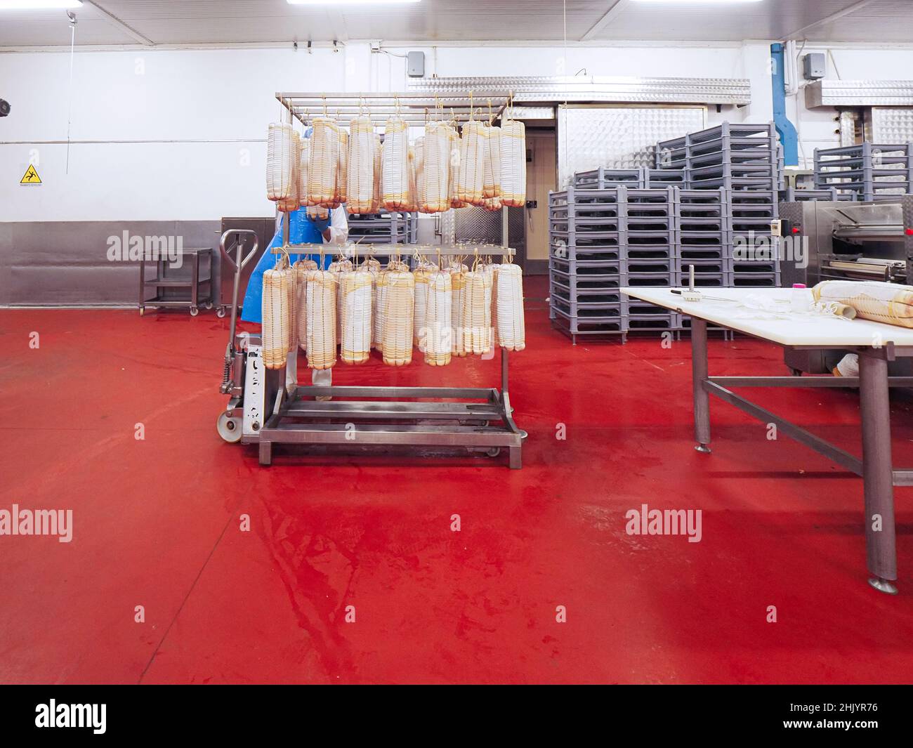 worker manufacturing, stuffing and tying sausages, salme and chorizo in cured meats production facility Stock Photo