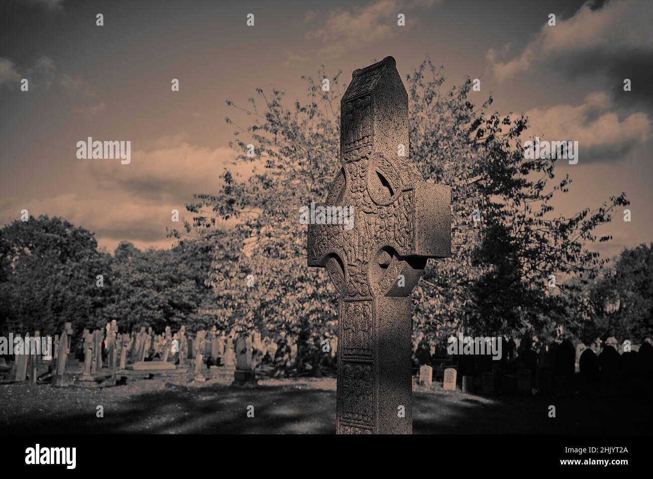 Mottled sunlight effect on Celtic Cross in churchyard in autumn Stock Photo