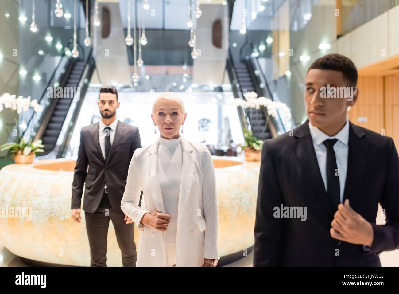 interracial security men escorting senior businesswoman in modern hotel Stock Photo