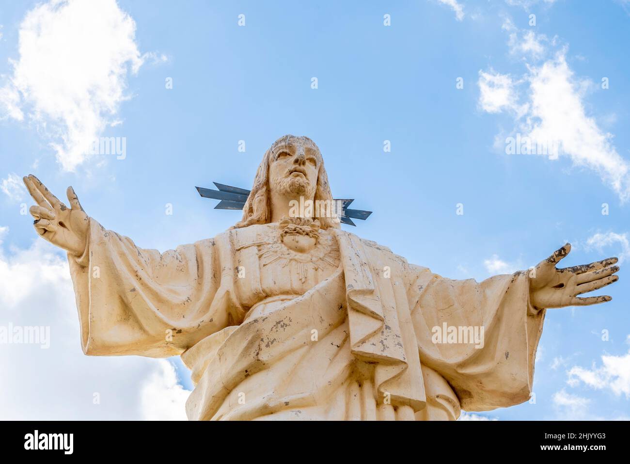 Corazon de Jesus religious statue above Puerto de Mazarron, Murcia, Spain. Flaking and weathered. Bird droppings running down head Stock Photo