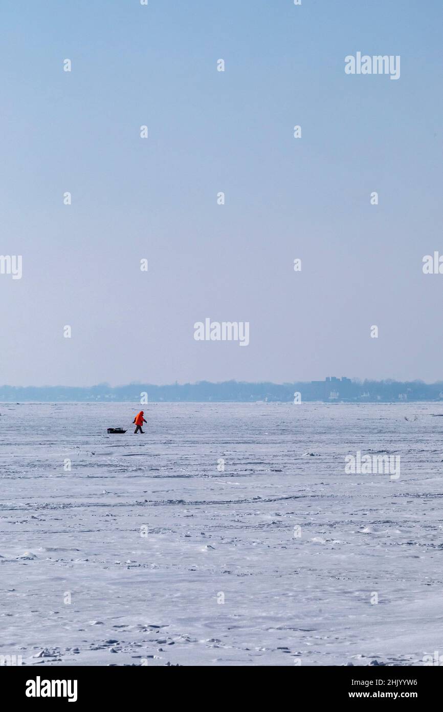 Harrison Township, Michigan - An ice fisherman hauls his gear over the frozen surface of Lake St Clair at Lake St Clair Metropark. Stock Photo