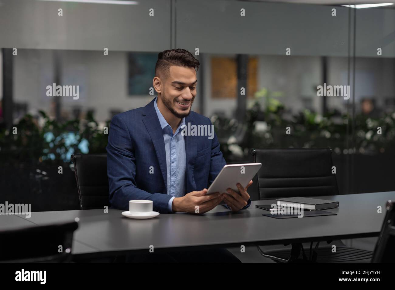 Smiling handsome middle eastern entrepreneur using digital tablet Stock Photo