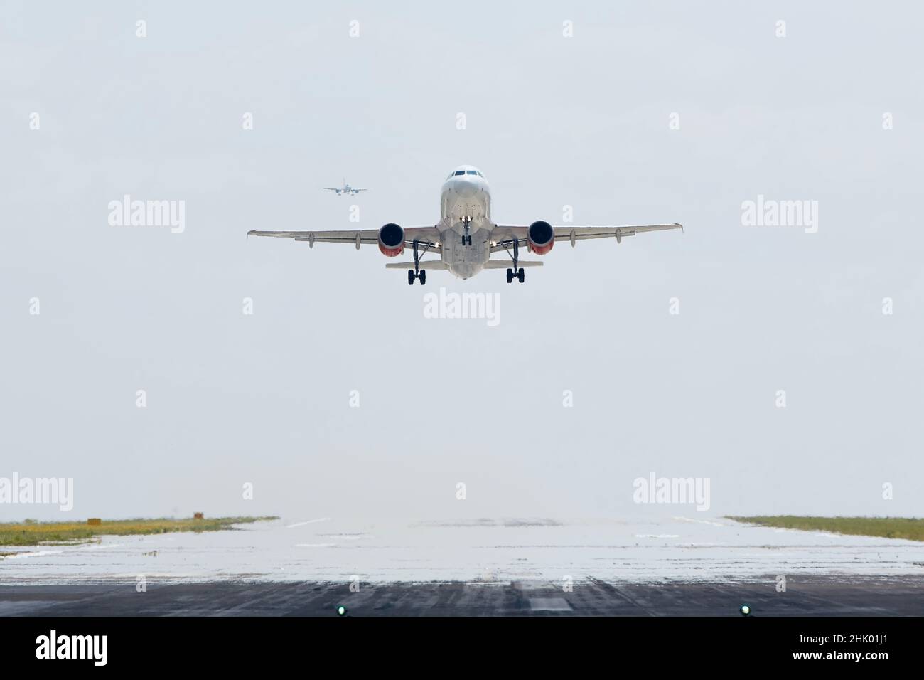 Airplane taking off from airport runway while another airplane is approaching to landing. Stock Photo