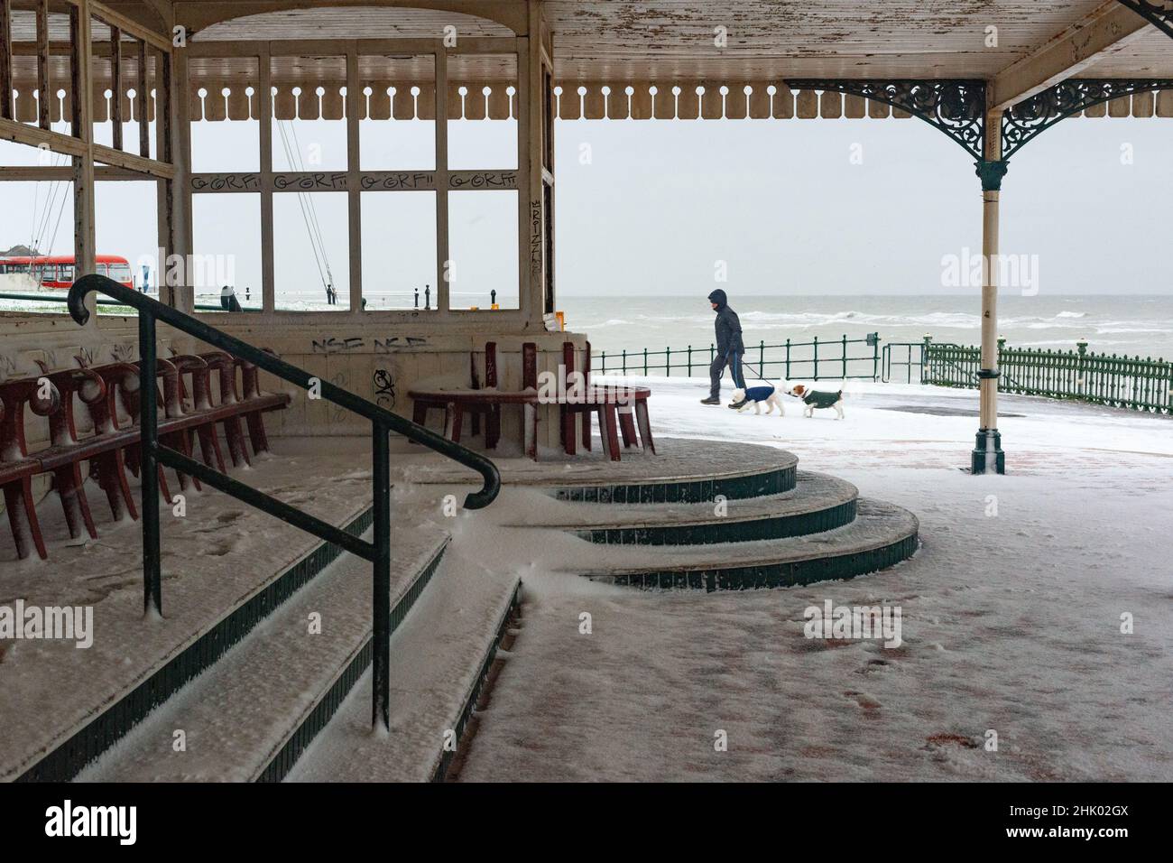 The dog walker by a beach shelter at Margate Main Sands in the snow, Margate, Kent Stock Photo
