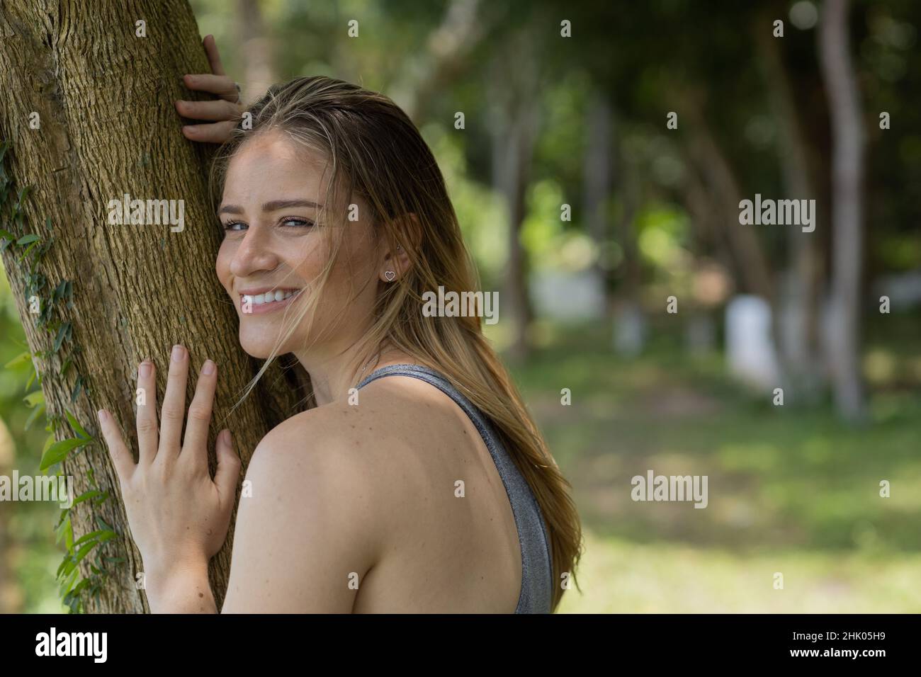 Portrait of smiling young woman at a park on a beautiful sunny day ...