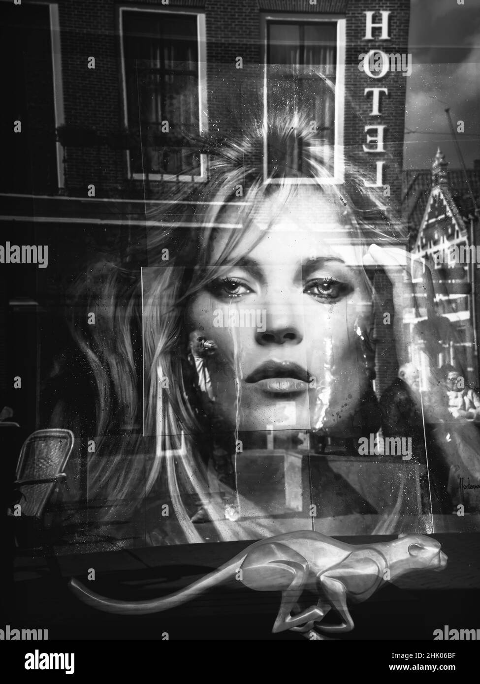 Black and white photo of reflection in a window of a woman looking longingly at the man in front of the hotel. Stock Photo