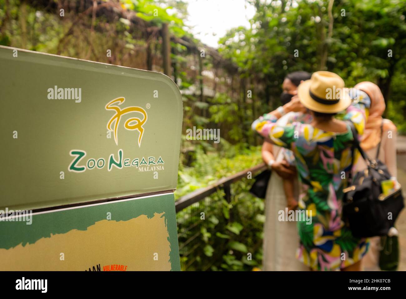 Kuala Lumpur, Malaysia- January 2022: Tourists visiting Zoo Negara next to sign and animal enclosure Stock Photo