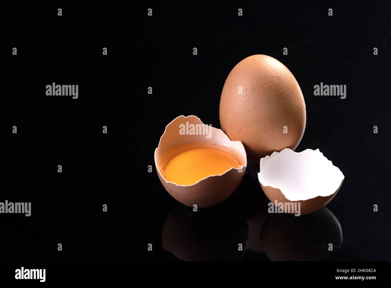 Egg and broken chicken egg isolated on black background with copyspace. Stock Photo