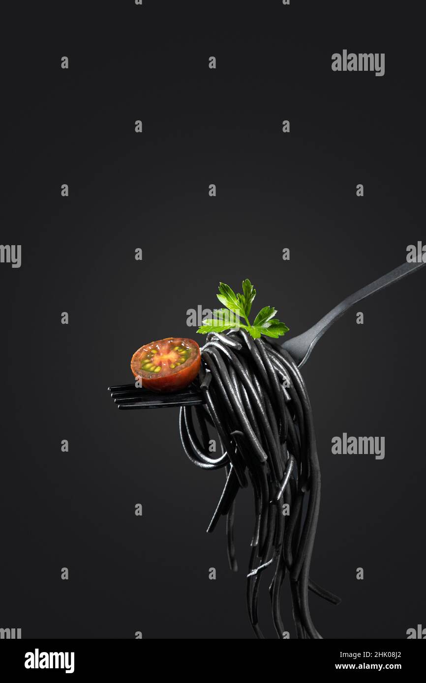 Black pasta rolled on a fork isolated on black background with