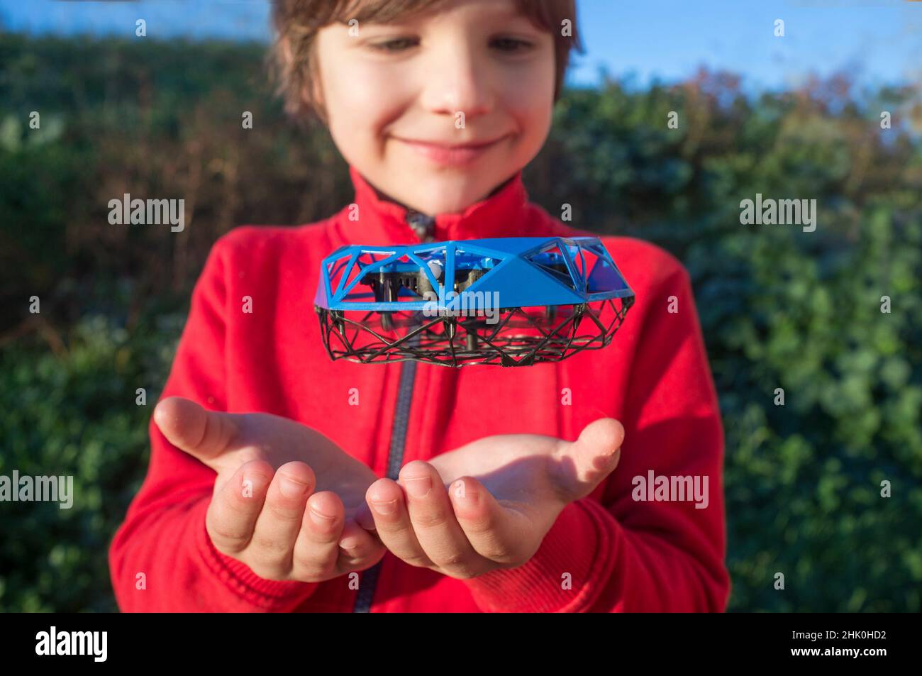 Child boy playing with toy dron. Little quadcopter flying over her hands. Stock Photo