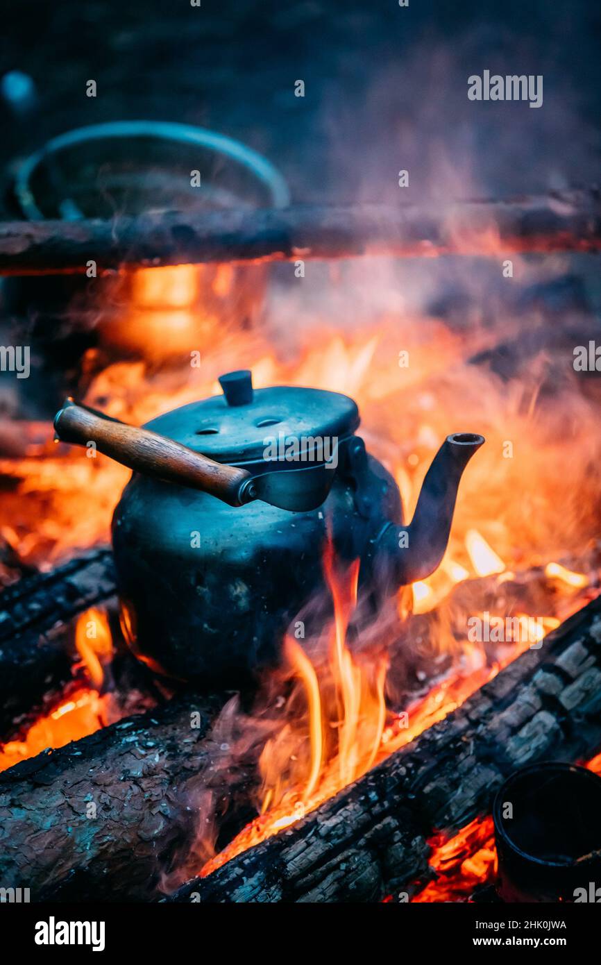 https://c8.alamy.com/comp/2HK0JWA/black-old-retro-iron-camp-kettle-boiling-water-on-a-fire-in-forest-bright-flame-fire-of-bonfire-at-dusk-night-2HK0JWA.jpg