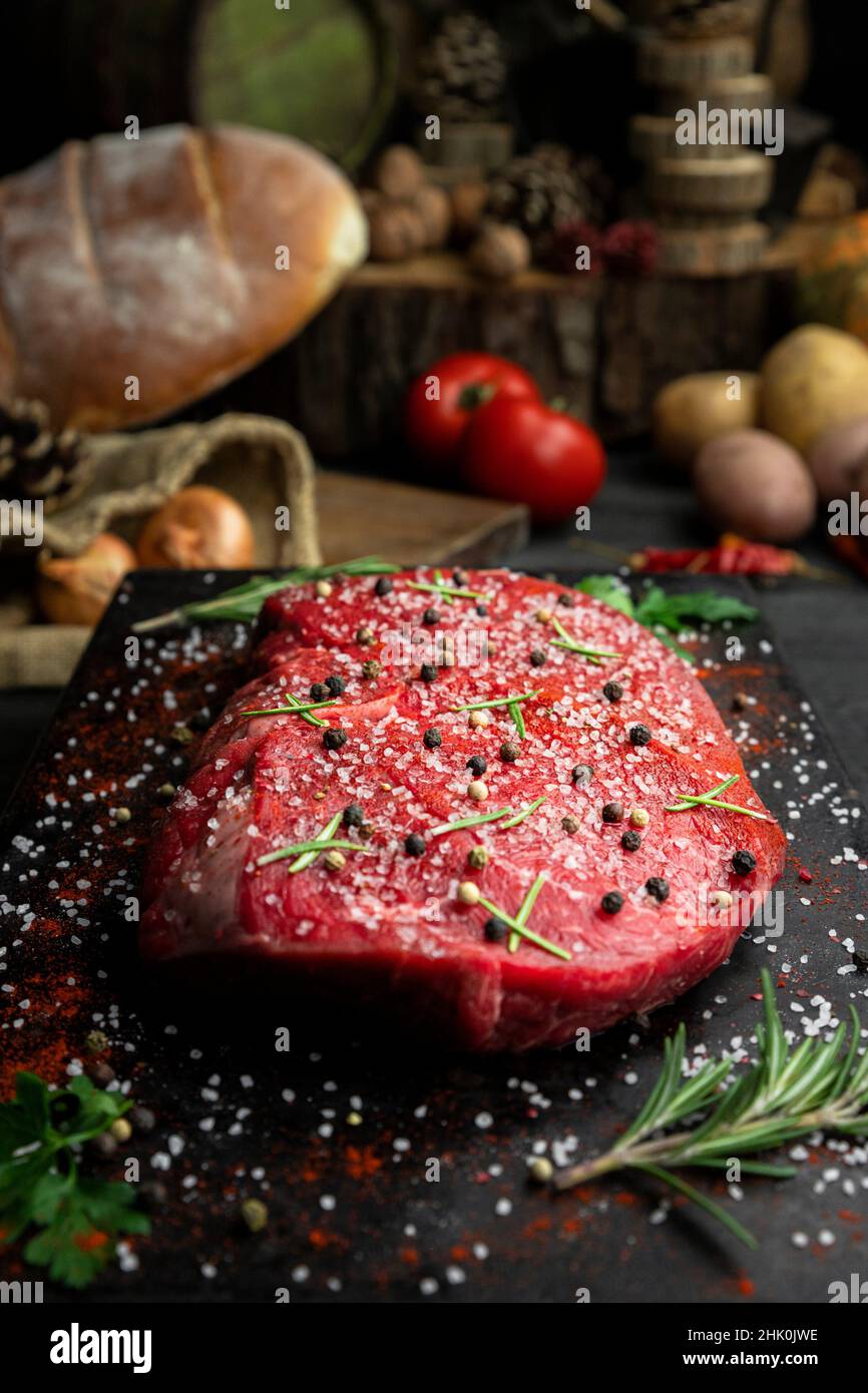 Raw beef steak seasoned with salt, pepper and fresh hearbs in the