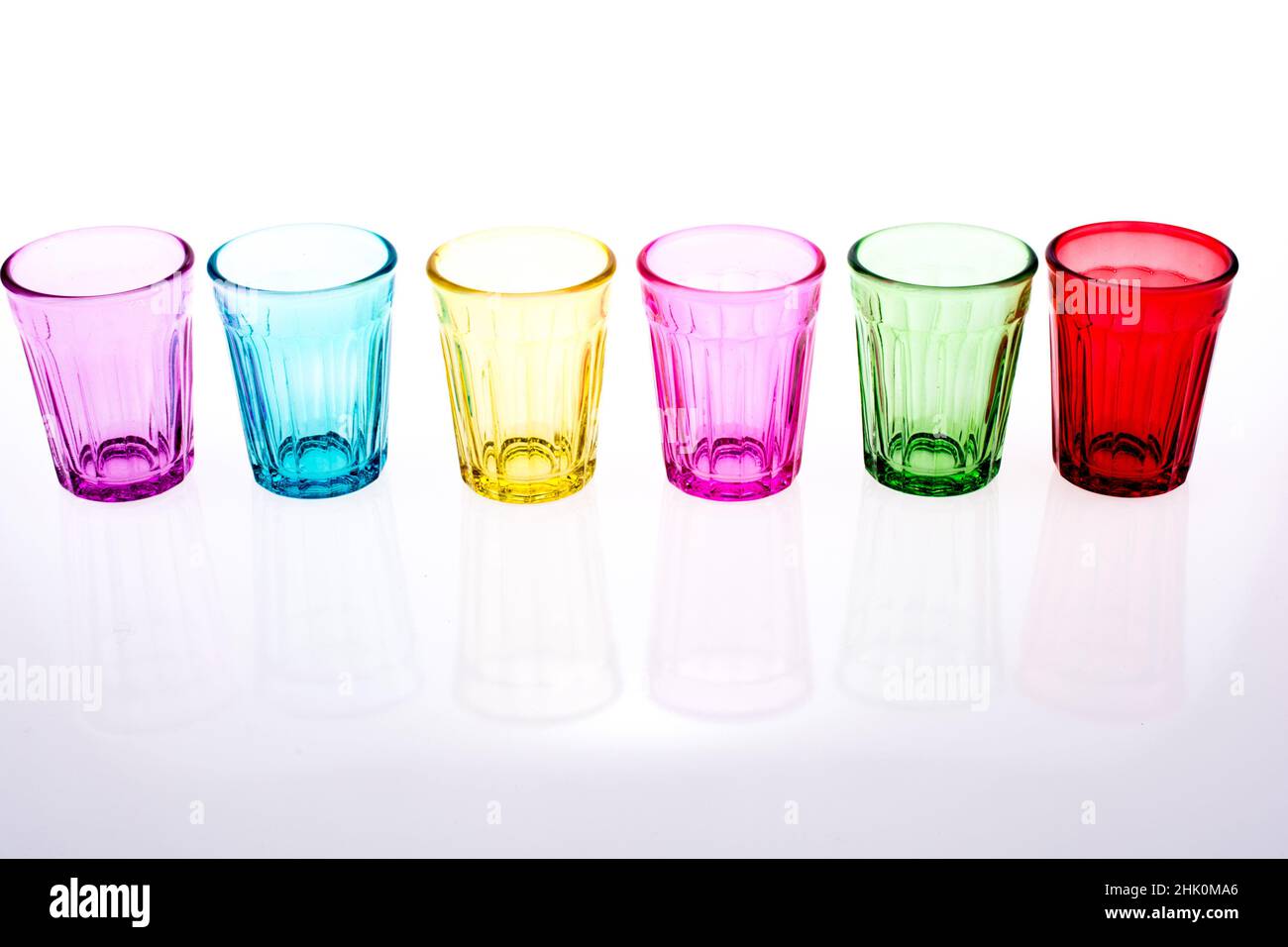 Colorful drinking glass lined up on white background. Stock Photo