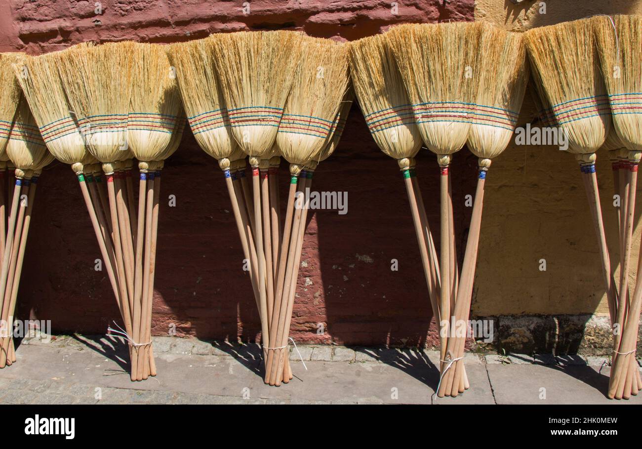 Set of yellow straw broom in a bazaar. Stock Photo