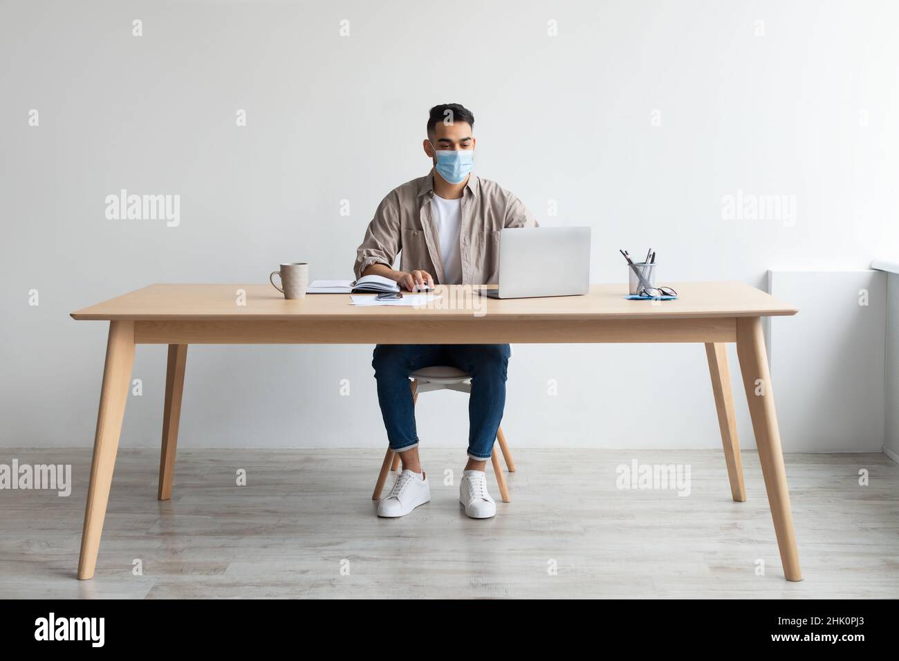Man in protective facemask working on pc at home office Stock Photo