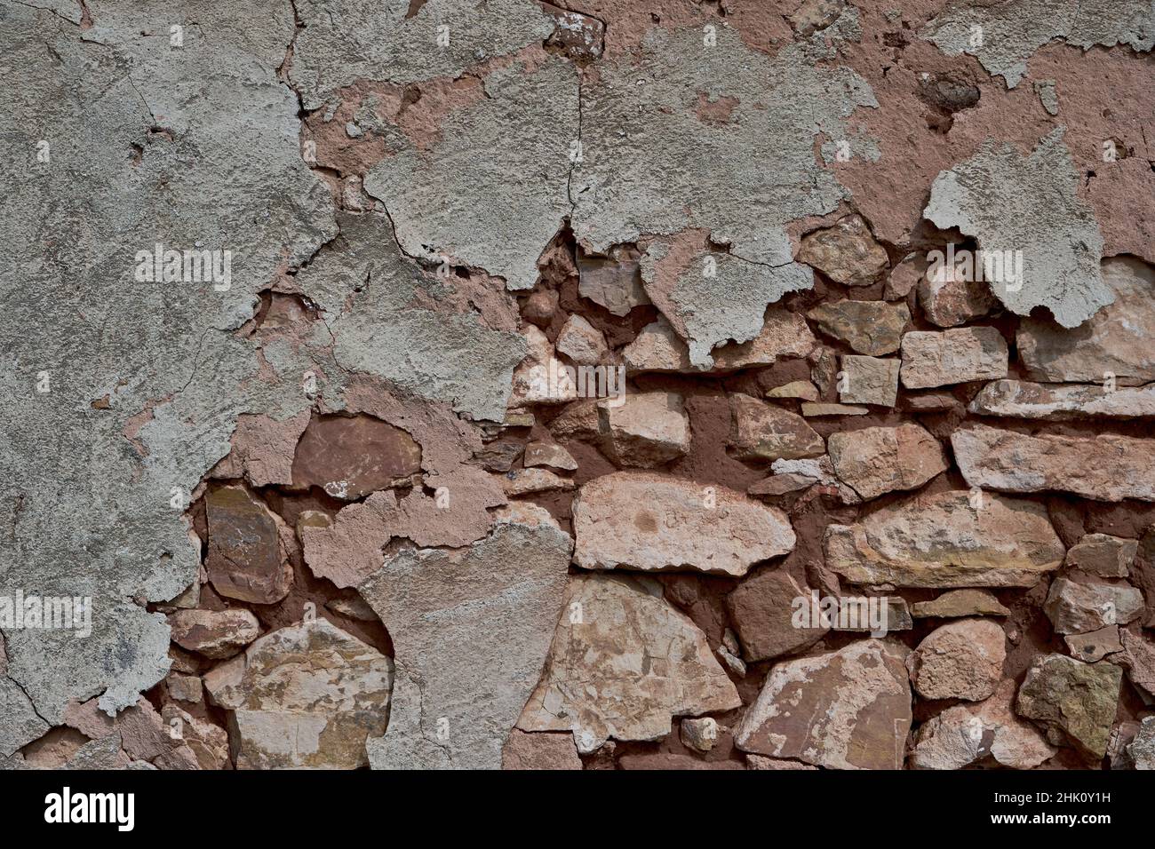 Old traditional limewashed stone wall with peeling plaster, white rustic background or texture Stock Photo