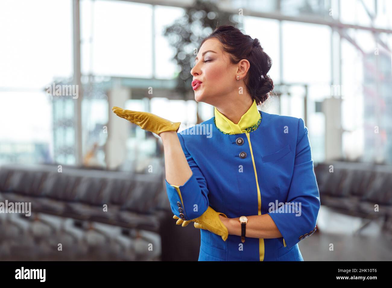 Female flight attendant blowing kiss at airport terminal Stock Photo