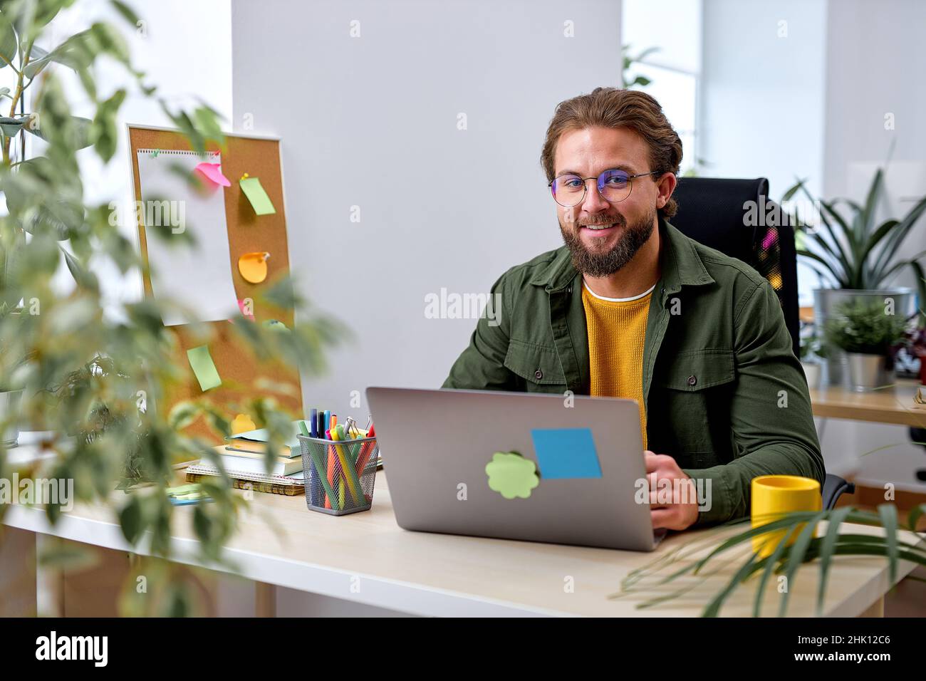 Successful businessman working on laptop at office. Businessman sitting at office desk working on new project, smiling, feeling happy. handsome caucas Stock Photo