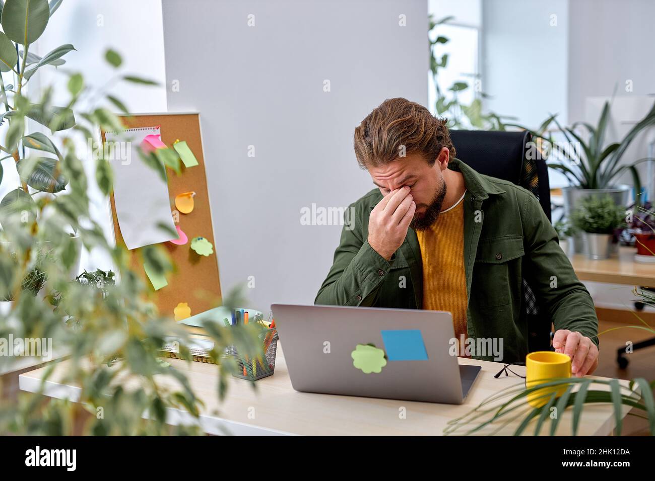 remote job, technology and people concept. tired young man with laptop computer working, want to go home, exhausted by work in office. alone. bearded Stock Photo