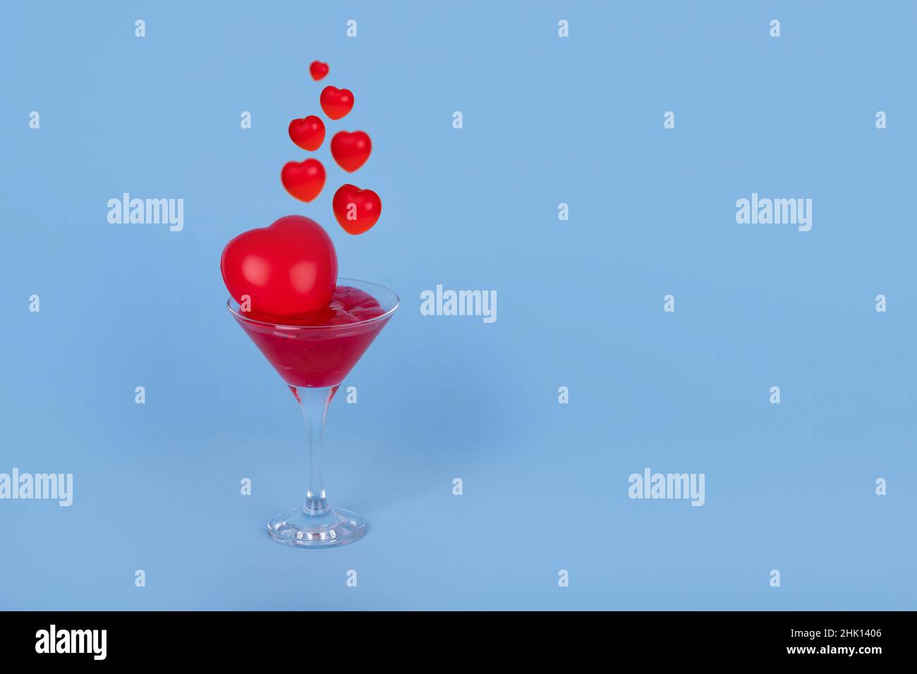 Valentine cocktail with red hearts isolated on a blue background. Creative love concept. Valentines Day. Trendy, minimalist card with copy space. Stock Photo