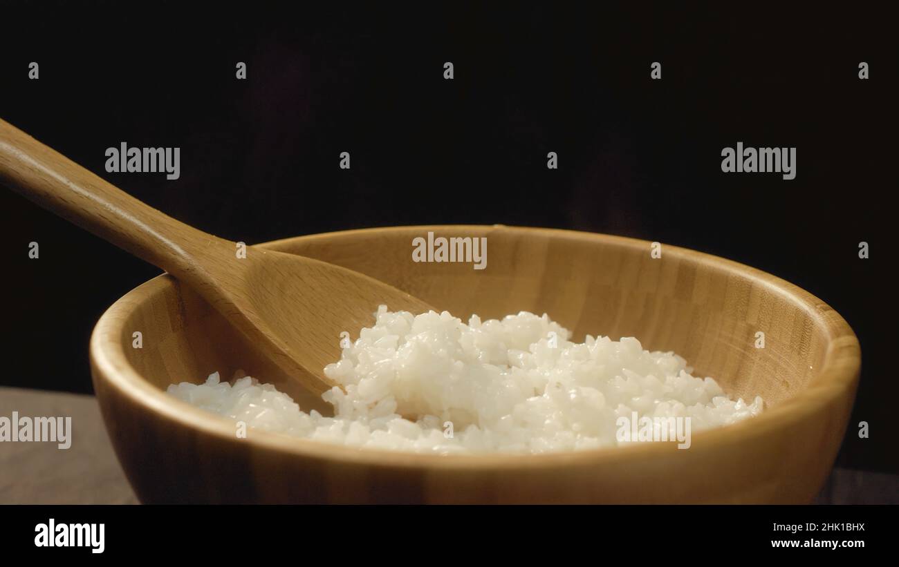Close-up of wooden bowl with hot rice and wooden spoon. Appetizing rice ...