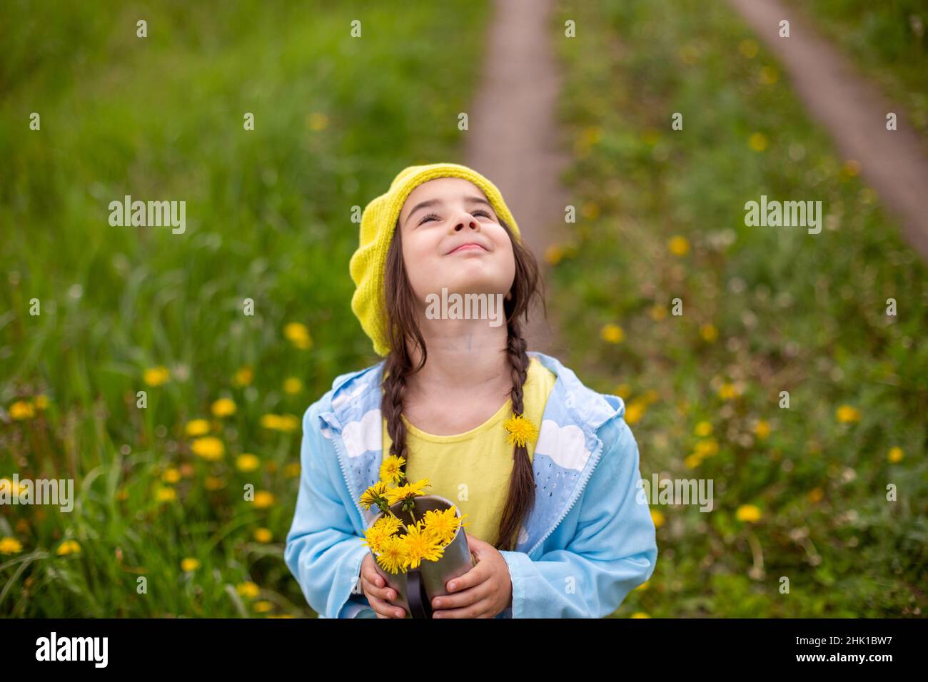 Portrait of a beautiful little girl with two pigtails holds a bouquet ...