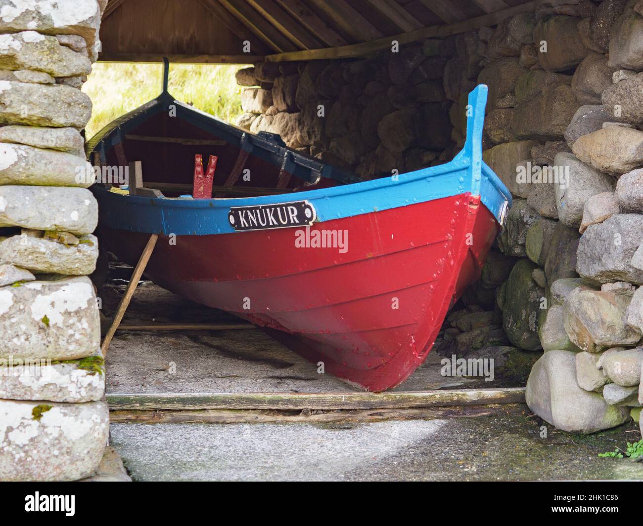 Sydradalur Faroe Islands - Oct, 2020: Red wooden boat in the stone house of Syðradalur near the harbor on the island of Kalsoy, Faroe Islands, Norther Stock Photo