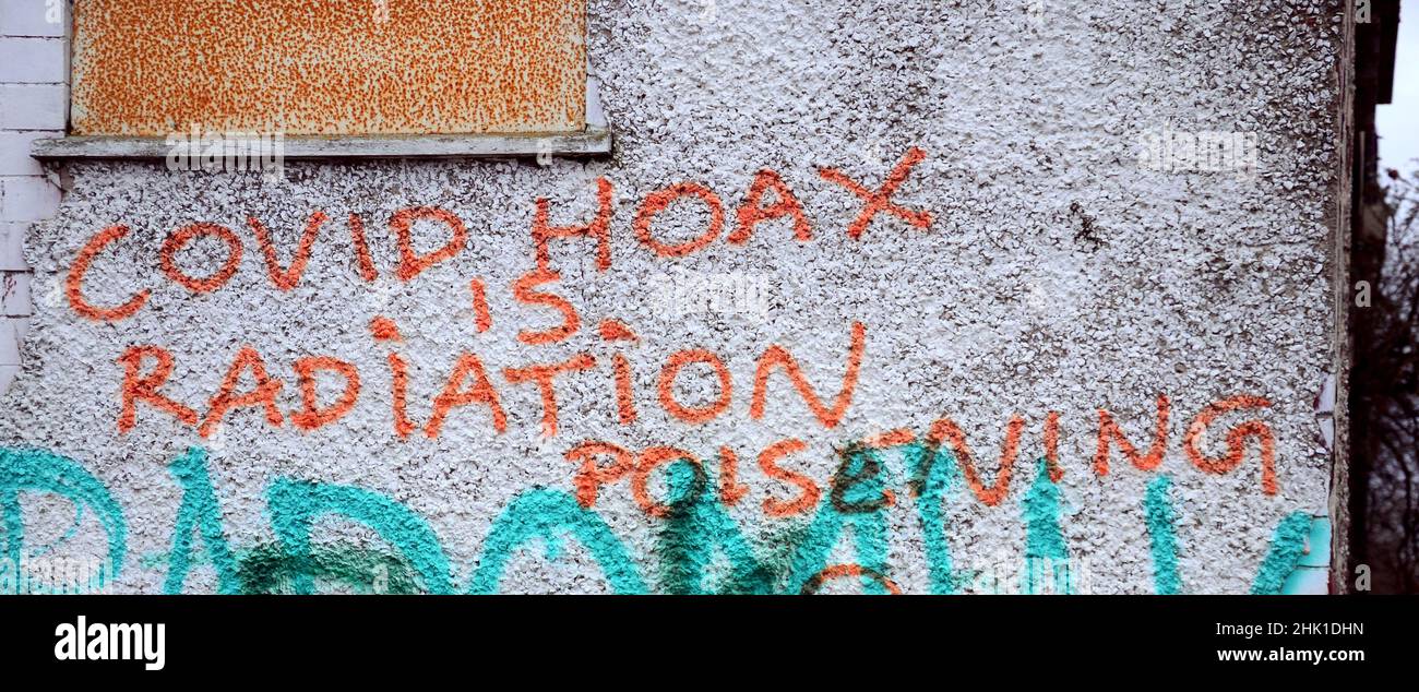 Graffiti on a wall Manchester, England, UK, says: ' Covid Hoax Is Radiation Poisening (sic)'. False claim virus is  a cover-up for radiation sickness. Stock Photo